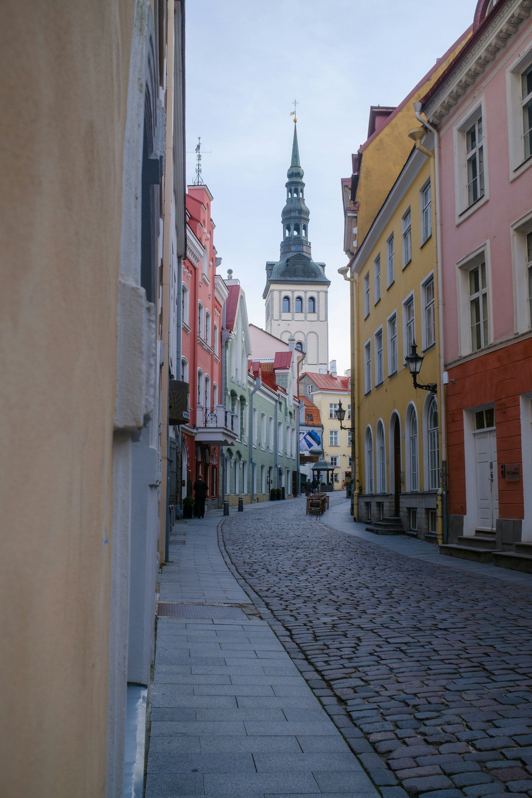 A quiet street in Tallinn, with stone buildings and a church tower.