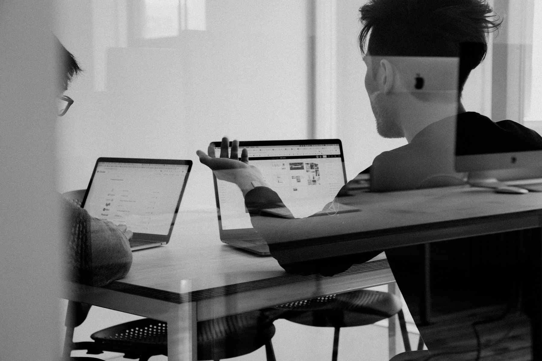 Two colleagues working through a screen together.